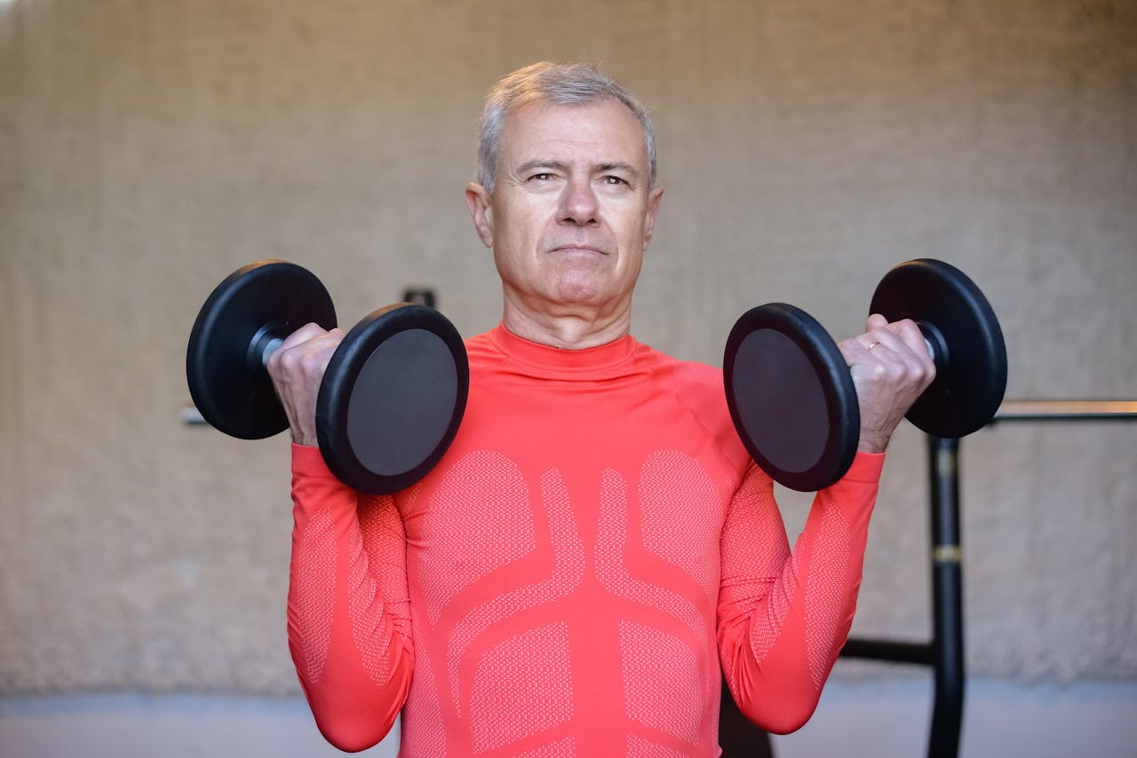 portfolio-img-01 Elderly man in red lifting dumbbells, promoting fitness and healthy aging indoors.
