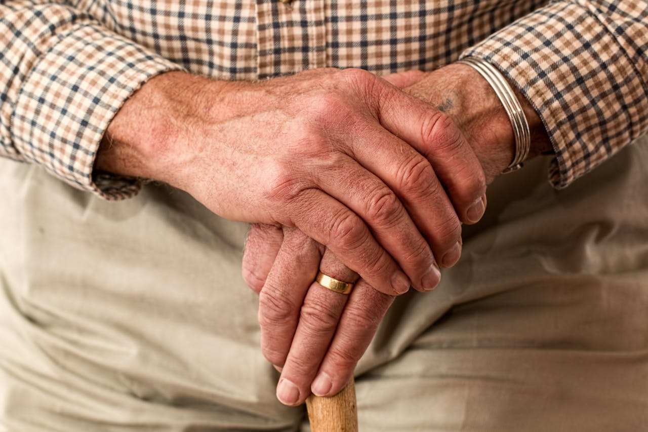 portfolio-img-03 A detailed image of elderly hands clasping a wooden cane, symbolizing aging and support.